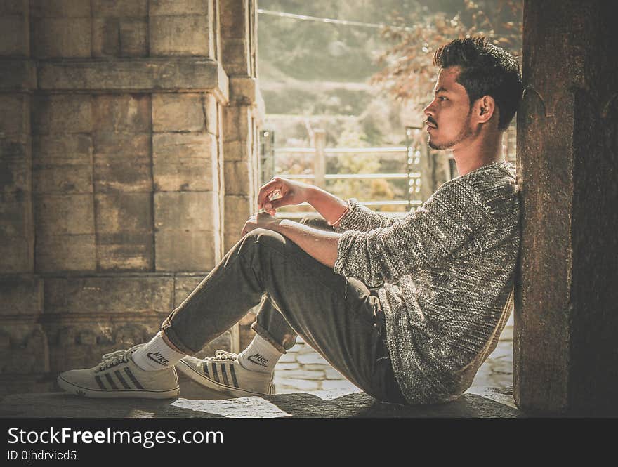 Photo of Man Wearing Gray Sweater and Track Pants Leaning on Wall