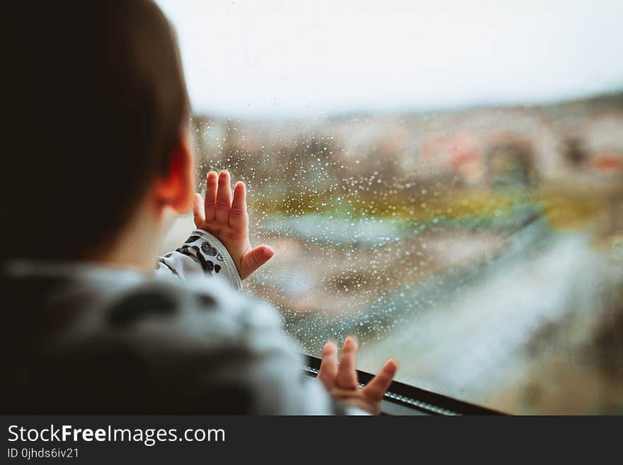 Selective Focus Photography of a Baby Looking Through The Window