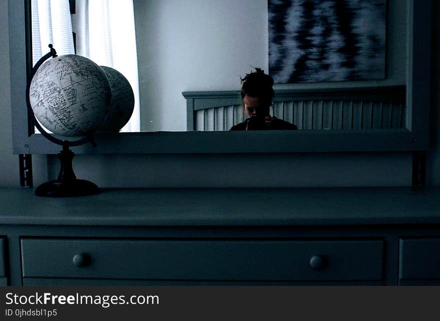 Woman in Front of Dresser With Mirror With Desk Globe