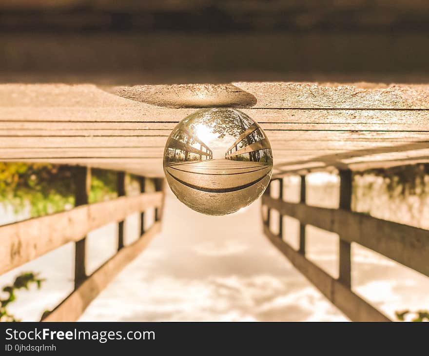 Macro Photography of Round Glass Ball on Top of Brown Wooden Dock