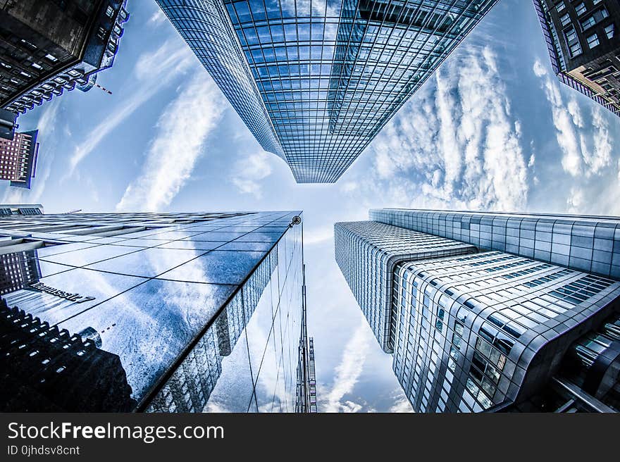 Low-angle Photo of Four High-rise Curtain Wall Buildings Under White Clouds and Blue Sky