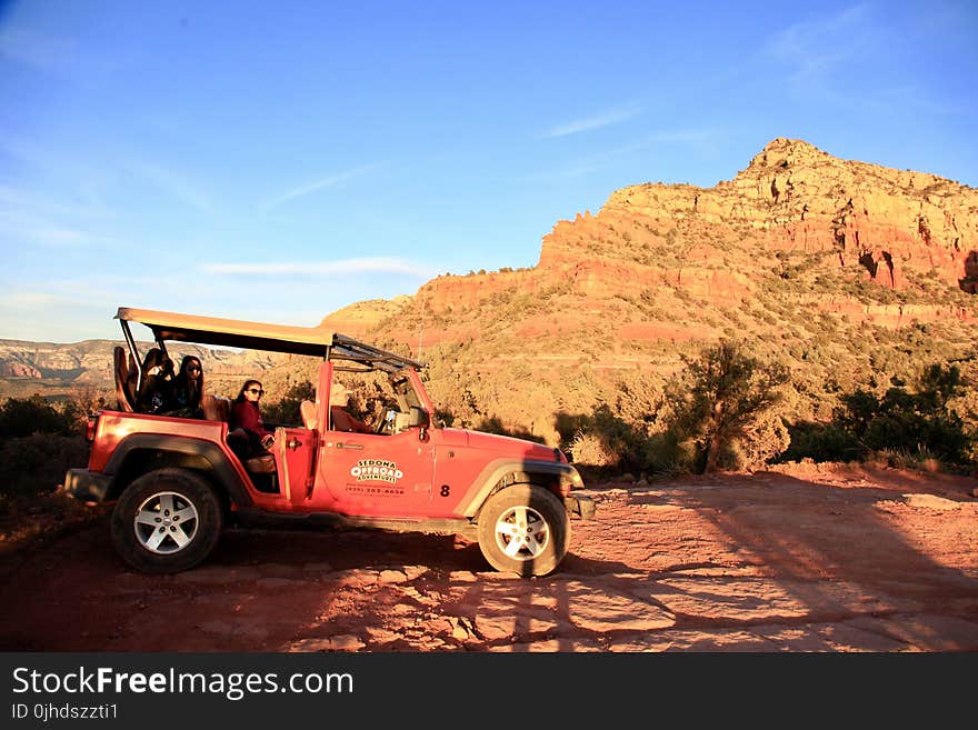 Red All-terrain Vehicle on Brown Rock Field during Sunset