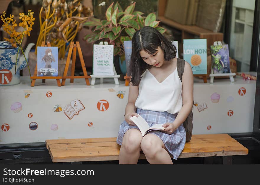 Woman Reading a Book While Sitting on a Bench