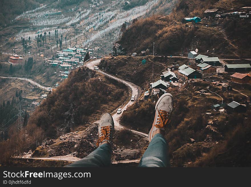 Person Wearing White Sneakers With Overlooking of Village on Hills