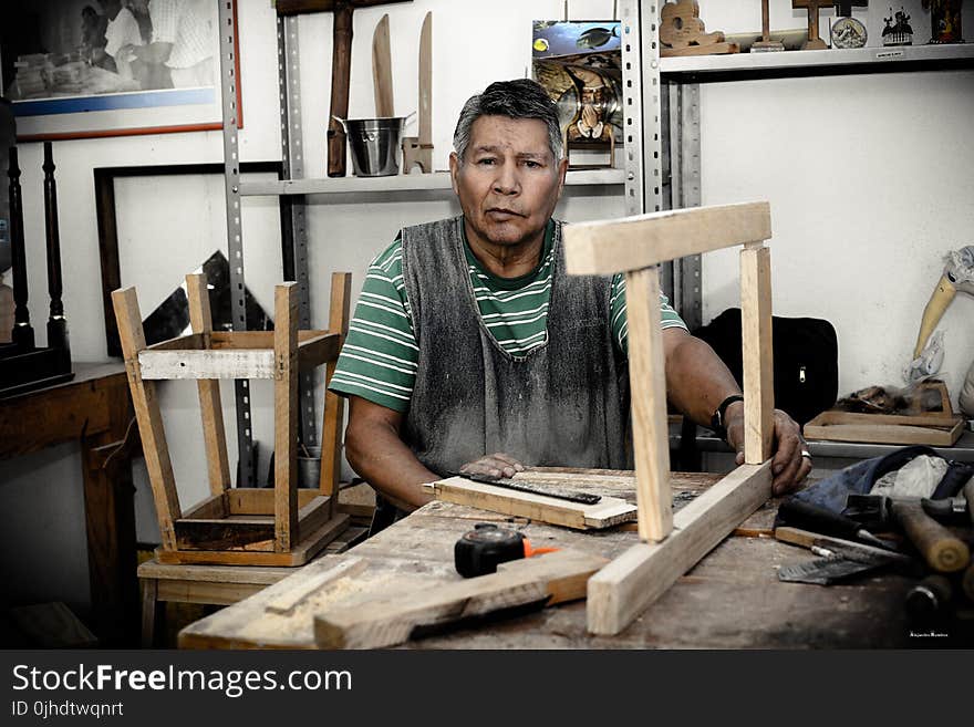 Man Wearing Green and White Stripe Shirt Holding Beige Wooden Frame on Table