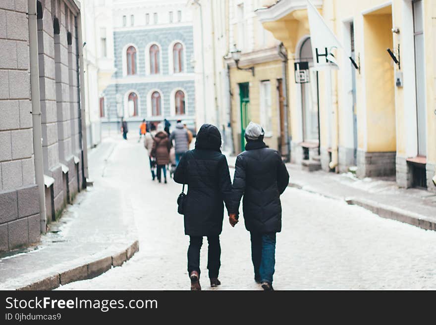 Couple Holding Hands Between of High Rise Building at Daytime