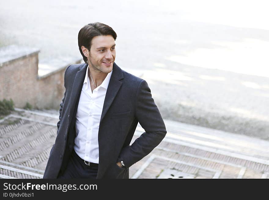 Man in White Dress Shirt and Black Blazer Standing Outside Building