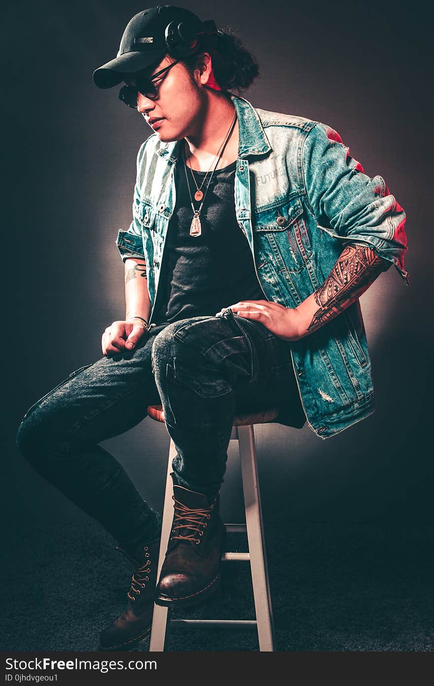 Man Wearing Denim Jacket While Sitting on Chair