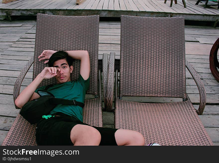 Man Wearing Green Shirt and Black Shorts Laying on Lounger