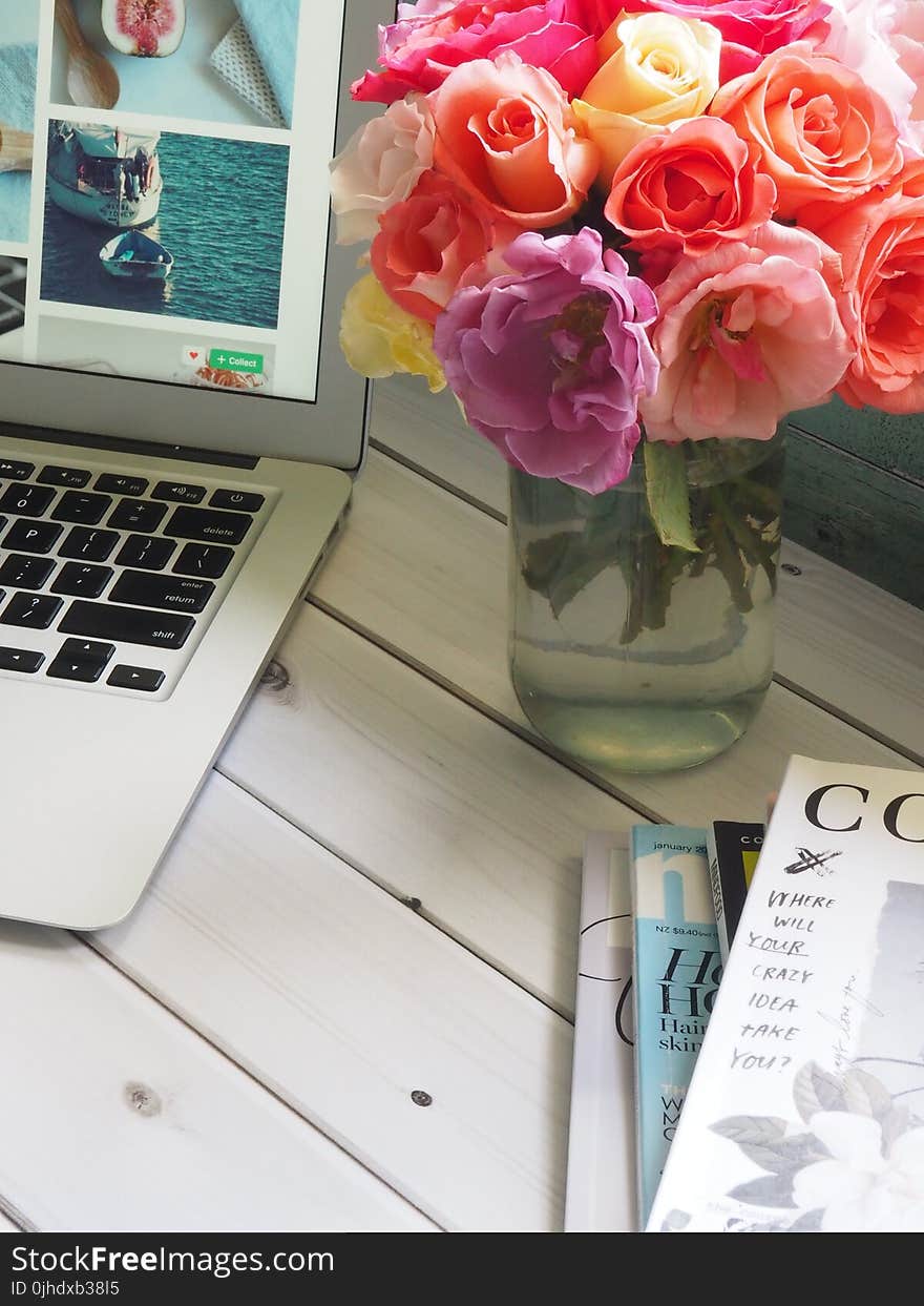 Assorted-color Flower Arrangement in Clear Glass Vase Beside a Laptop