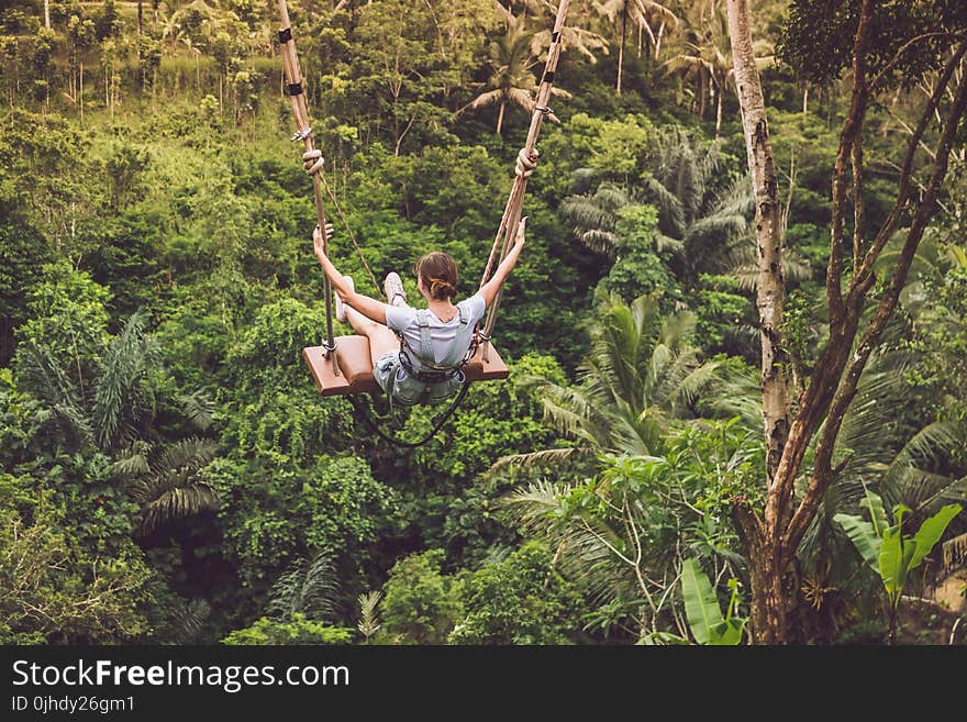 Woman Riding Hanging Swing in Forest