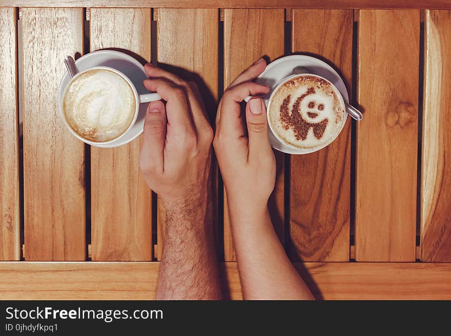 Person Holding Cup of Coffees on Table