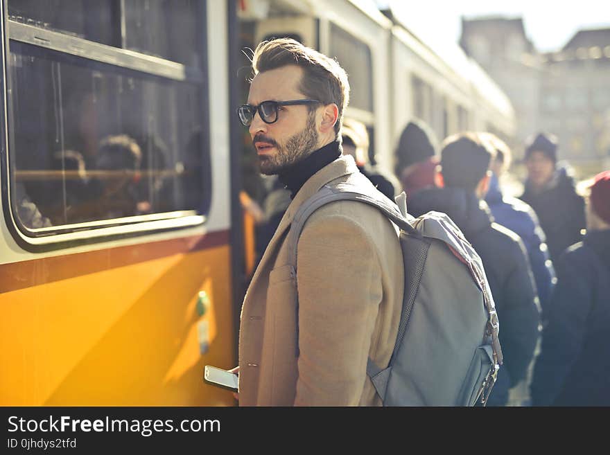 Man in Brown Coat and Gray Backpack Posing for a Photo