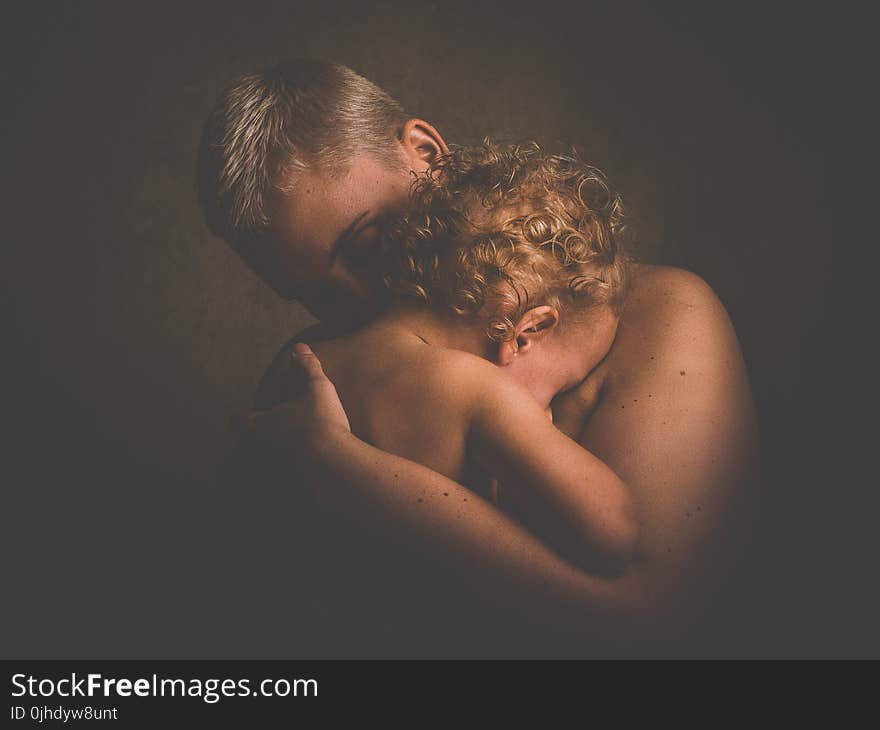 Photo of Topless Person Carrying Curly Haired Child