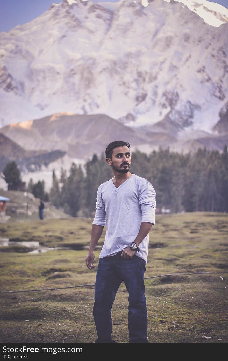 Man in Grey V-neck Long-sleeved Shirt With Blue Denim Jeans Behind White Mountain