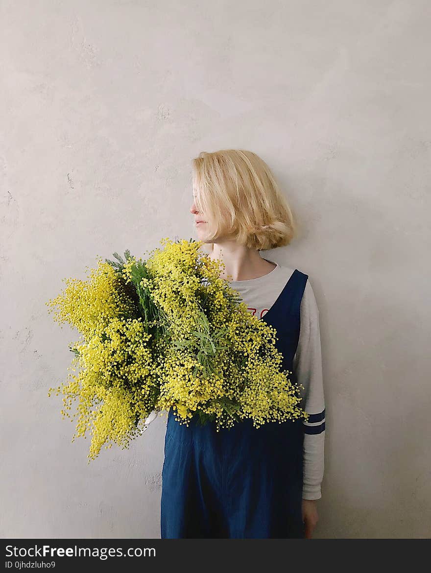 Woman Wearing Blue V-neck Sleeveless Top While Holding Yellow Petaled Flower