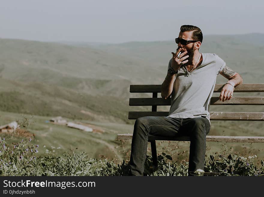 Photo of a Man Sitting on Wooden Bench