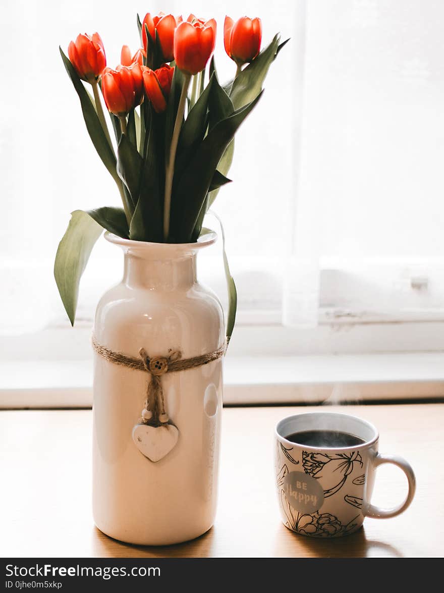 Red Tulips Flowers in White Ceramic Vase Beside Cup of Coffee