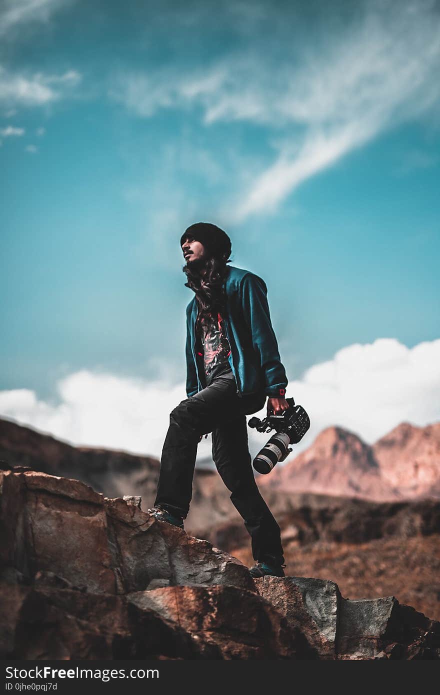 Man Wearing Blue Jacket Holding a White and Black Dslr Camera