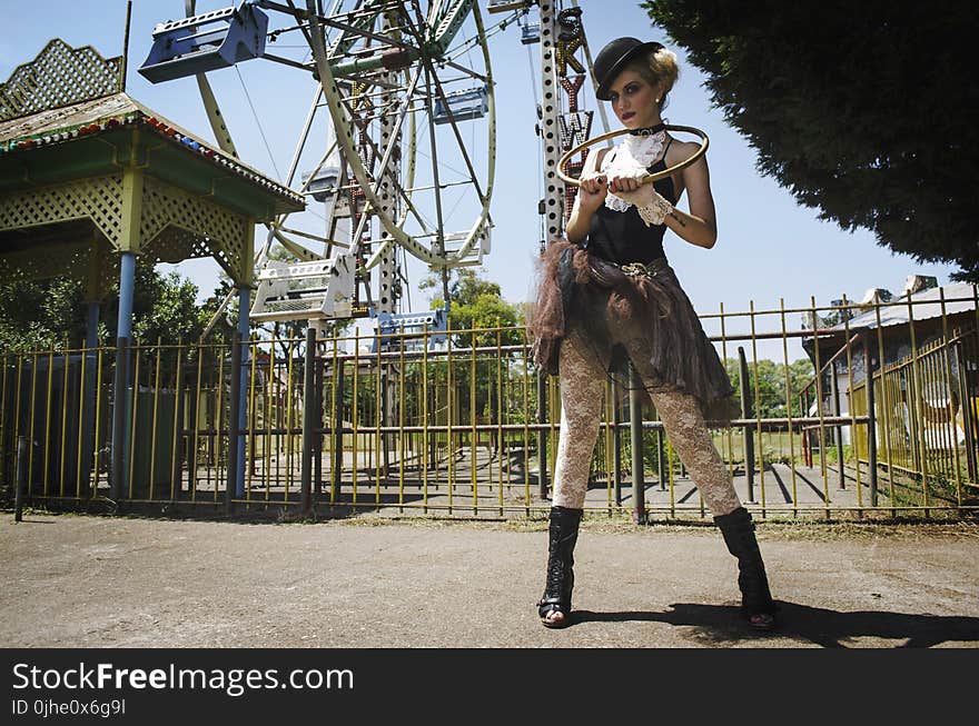 Woman in Black Camisole Top Stands Behind Ferris Wheel