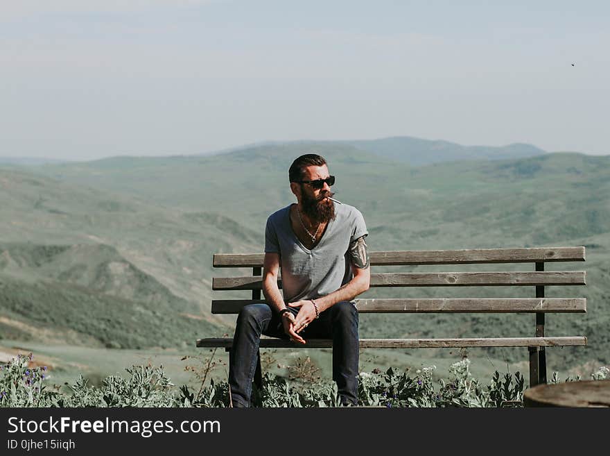 Photography of a Man Sitting on Wooden Bench