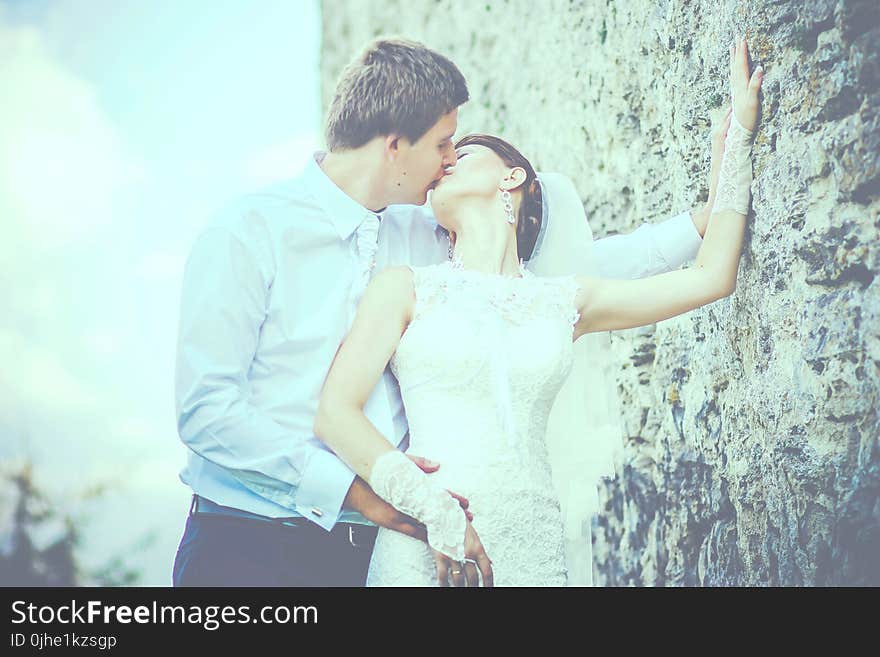 Man Kissing Woman Wearing Sleeveless Wedding Gown