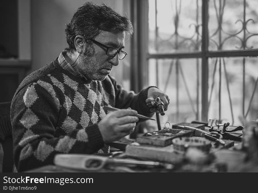 Grayscale Photo of Man Holding Tools