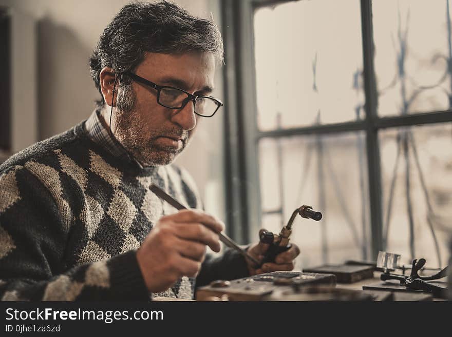 Man in Gray and Black Argyle Sweater Holding Acetylene Torch