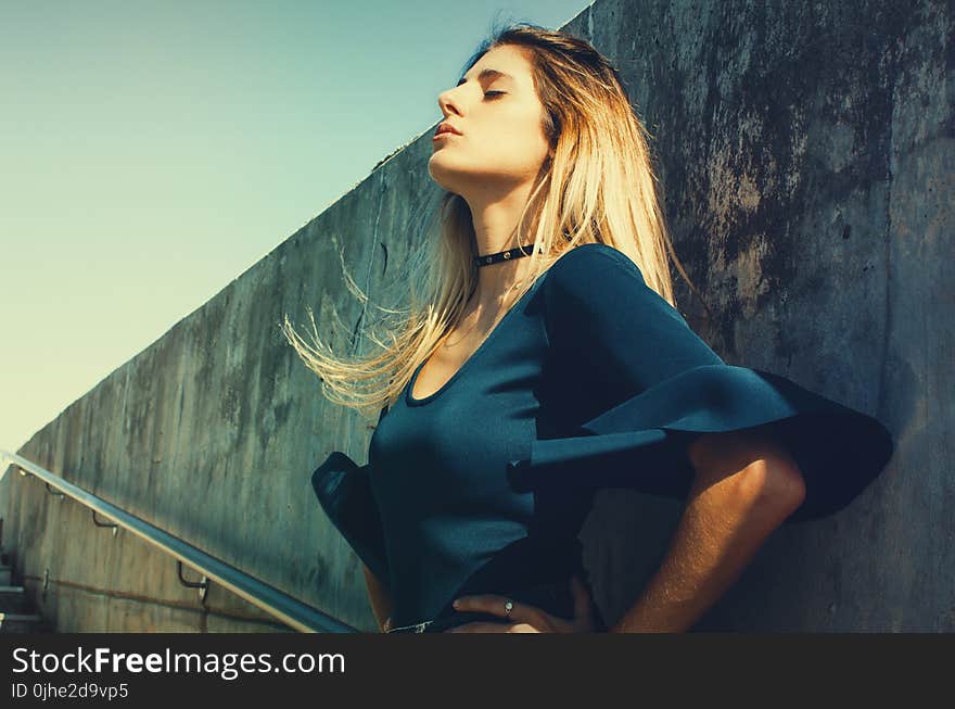 Woman Wearing Blue Scoop-neck Top Standing Near Gray Concrete Wall