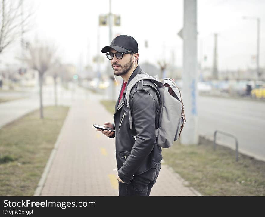 Man Wearing Black Leather Jacket Holding Smartphone