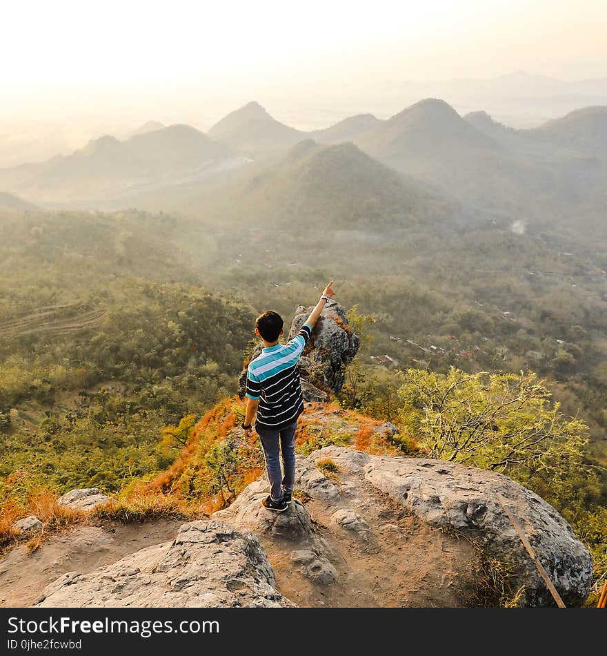 Photo of Man Standing on Rock Mountain Pointing Out Mountain