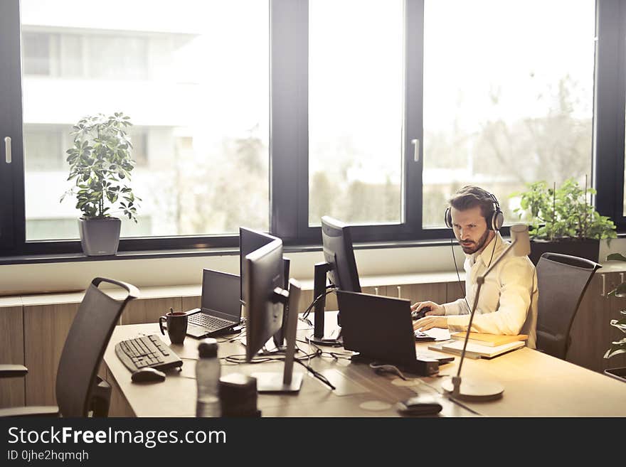 Man With Headphones Facing Computer Monitor