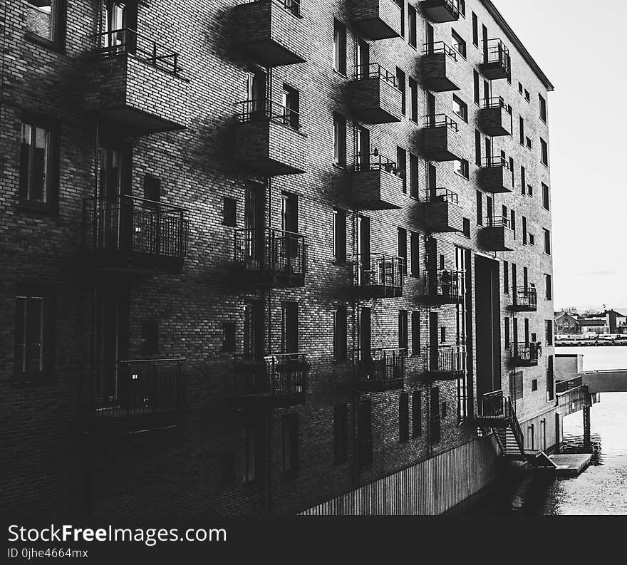 Grayscale Photo of Building Beside Body of Water