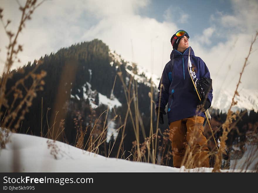 Low Angle Photography of Man Wearing Blue Jacket Carrying Snow Board