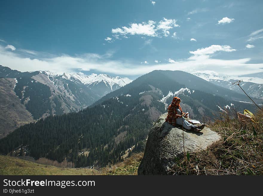 Person Sitting on Rock Near Cliff