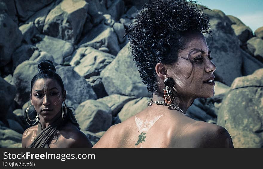 Photo of Two Women With Tattoos Standing Near Rocks