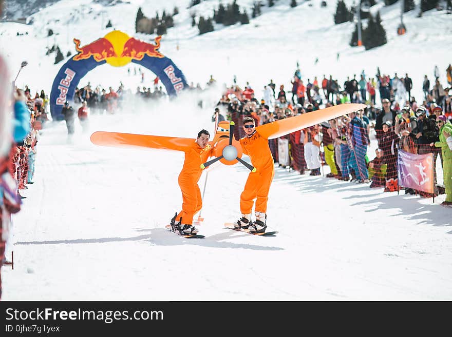 Photography of Men in Orange Suits Ridding Snowboard