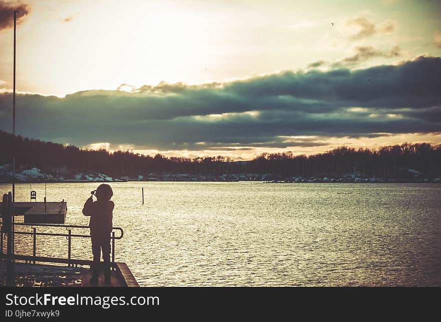 Silhouette of Person Standing on Dock