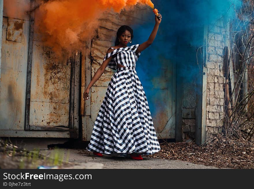 Woman in Black and White Plaid Dress Holding Torch