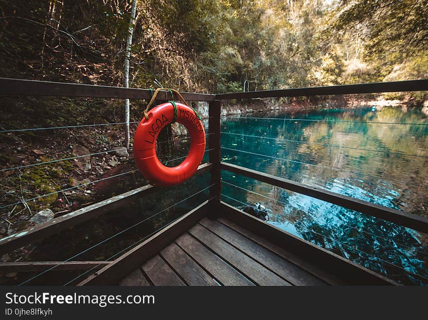 Red Life Buoy Hanging on Brown Wooden Balcony