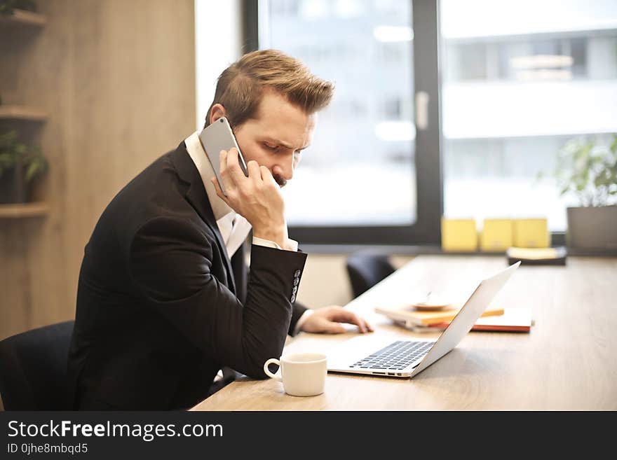 Man Having a Phone Call In-front of a Laptop