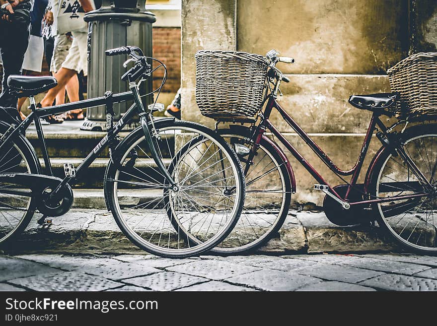 Two Black Bicycles Parting Near Wall