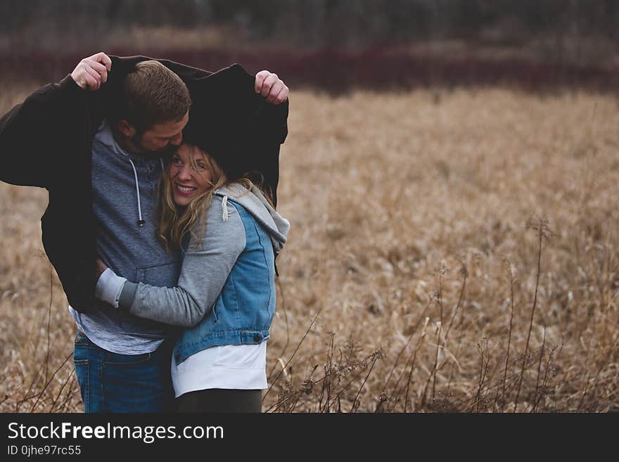 Man and Woman Hugging on Brown Field