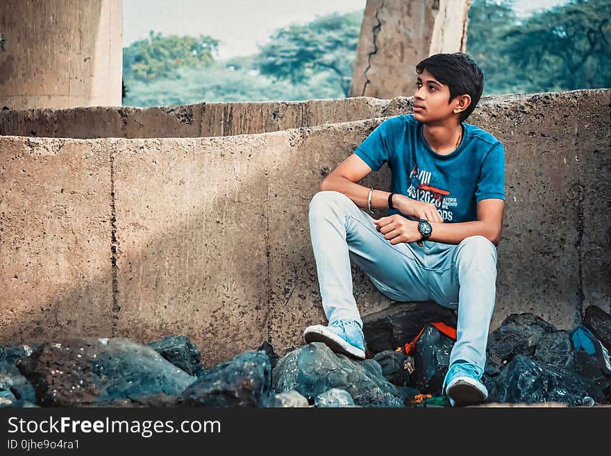 Man Sitting on Stone Leaning on Concrete Wall