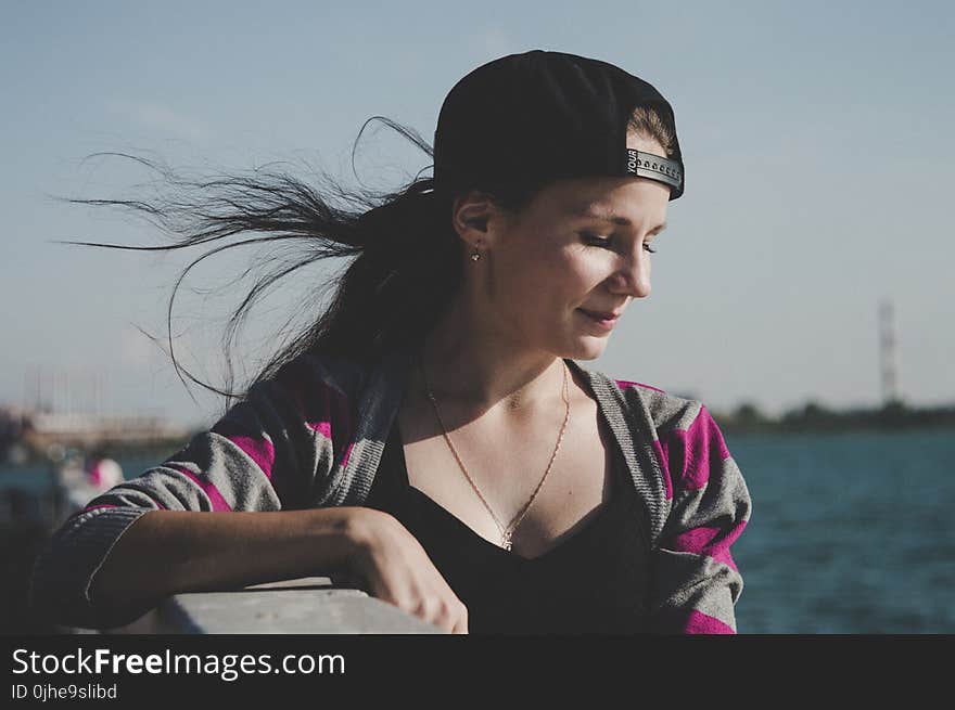 Selective Focus Photography of Female Wearing Black Snapback Near Ocean