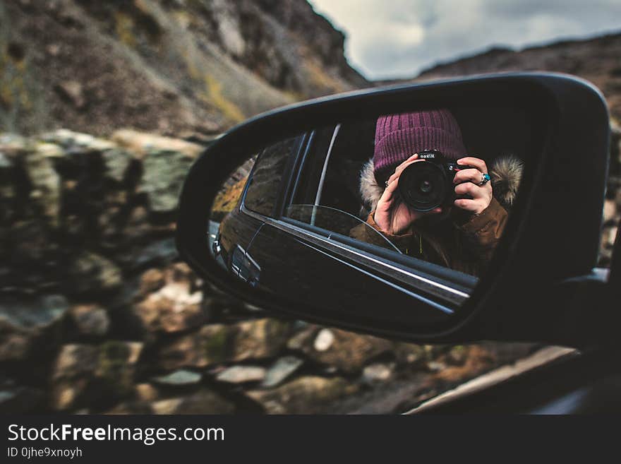 Person Holding Dslr Camera Reflected on Black Framed Wing Mirror