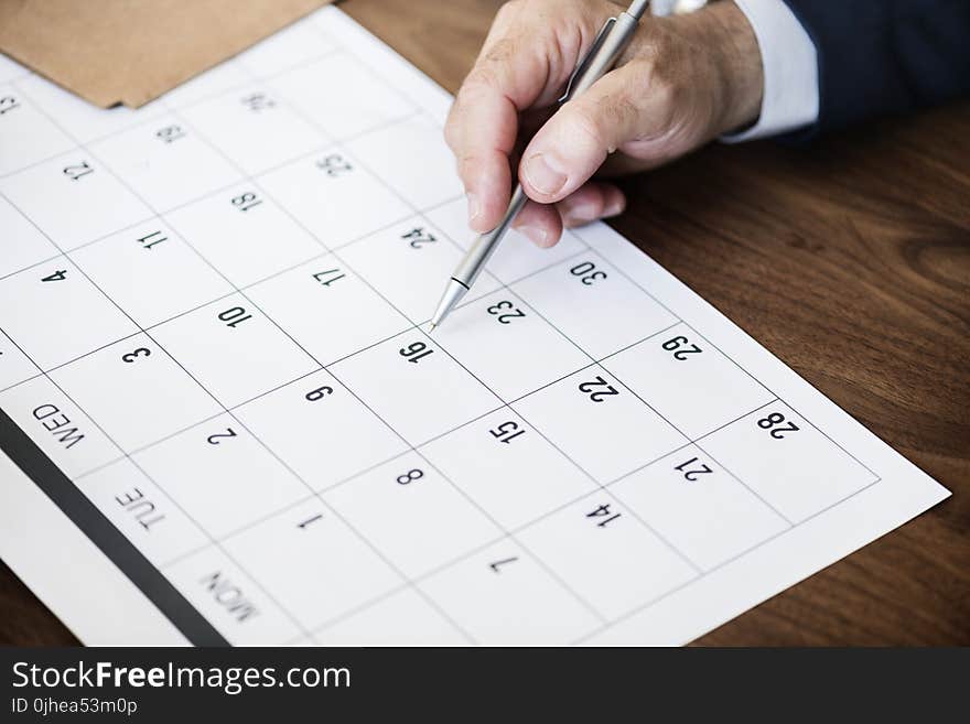 Person Pinpointing Pen on Calendar