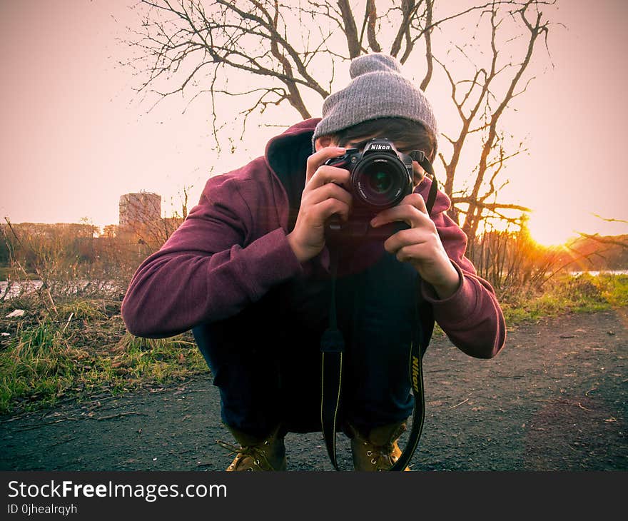 Man in Red Jacket Holding Black Dslr Camera