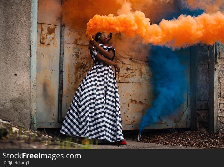 Woman in White and Black Dress Holding Orange Smoke