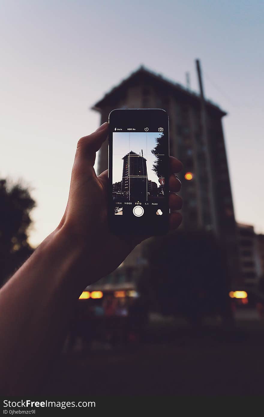 Person Holding Iphone Taking a Photo of Building